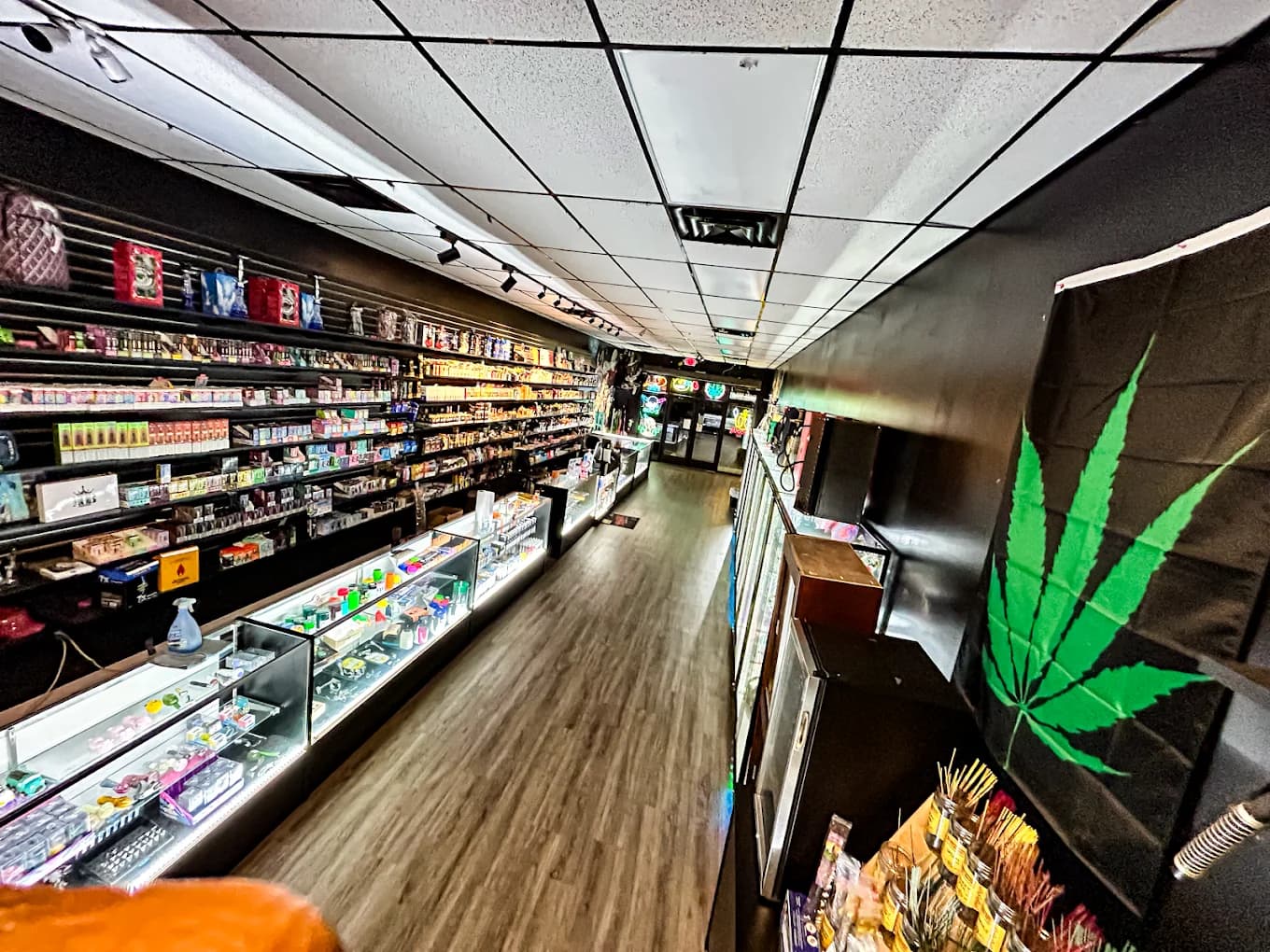 The THC aisle at Smoke Shop Kart, glass cases beneath the painted leaf mural.